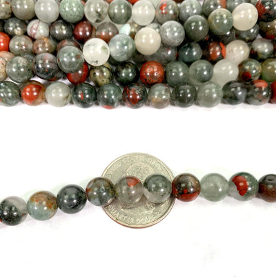 Close up African Bloodstone Polished Round Beads on Strand on top of a quarter for size reference. 