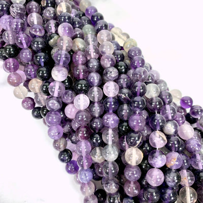purple fluorite bead strands spiraled together on a white background