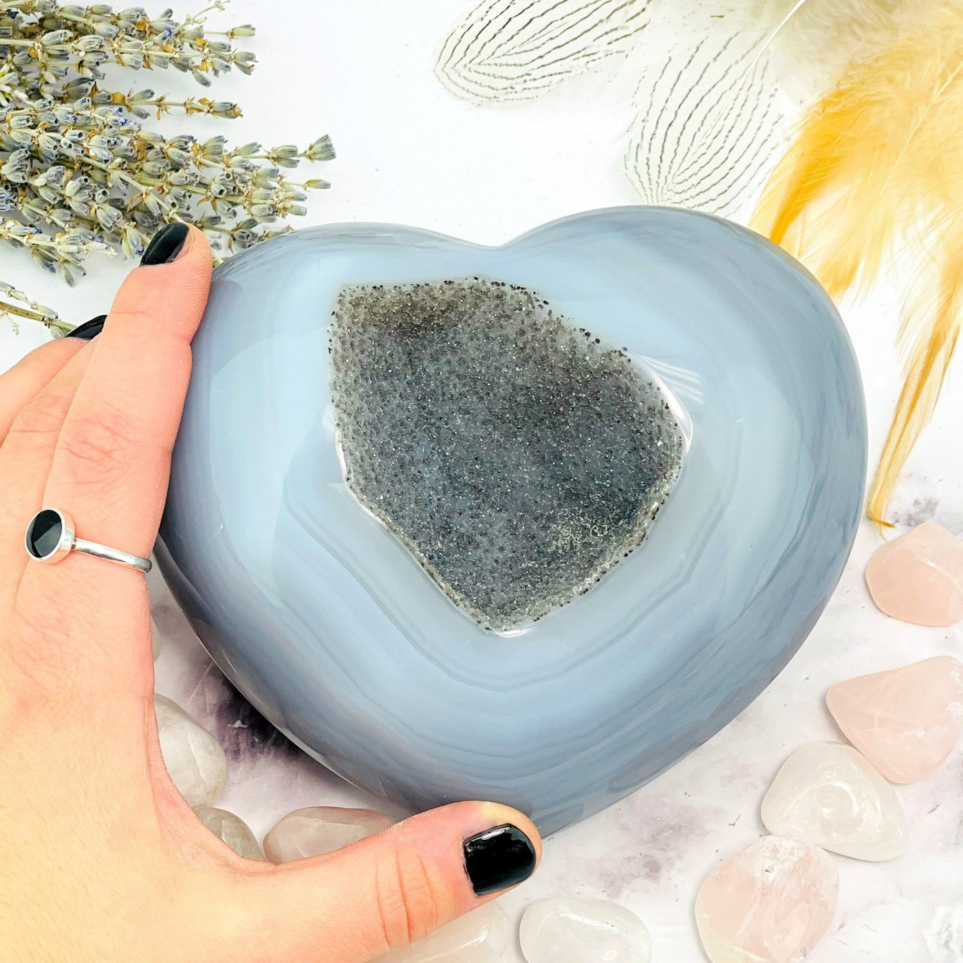 Druzy Natural Agate Heart Shaped Stone laying down flat next to a hand within an alter.