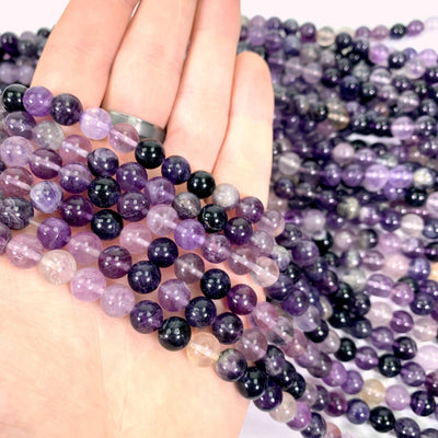 purple fluorite beads in hand with white background