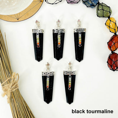 overhead view of five black tourmaline polished point pendants with chakra gemstone accent for possible variations