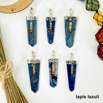 overhead view of six lapis lazuli polished point pendants with chakra gemstone accent for possible variations