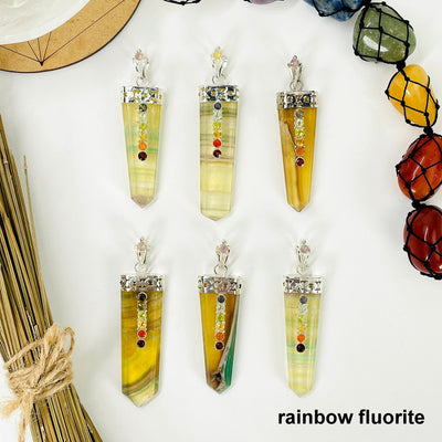 overhead view of six rainbow fluorite polished point pendants with chakra gemstone accent for possible variations