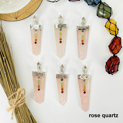 overhead view of six rose quartz polished point pendants with chakra gemstone accent for possible variations