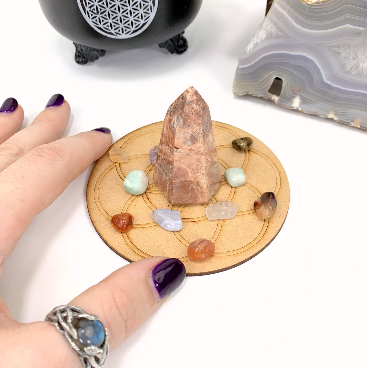 crystal grid decorated with crystals with a hand touching the left side of it with a white background