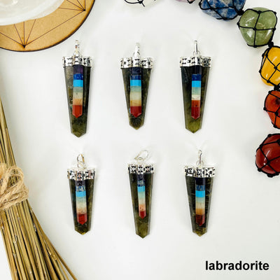 overhead view of six labradorite polished point pendants with chakra point accents on white background with decorations for possible variations
