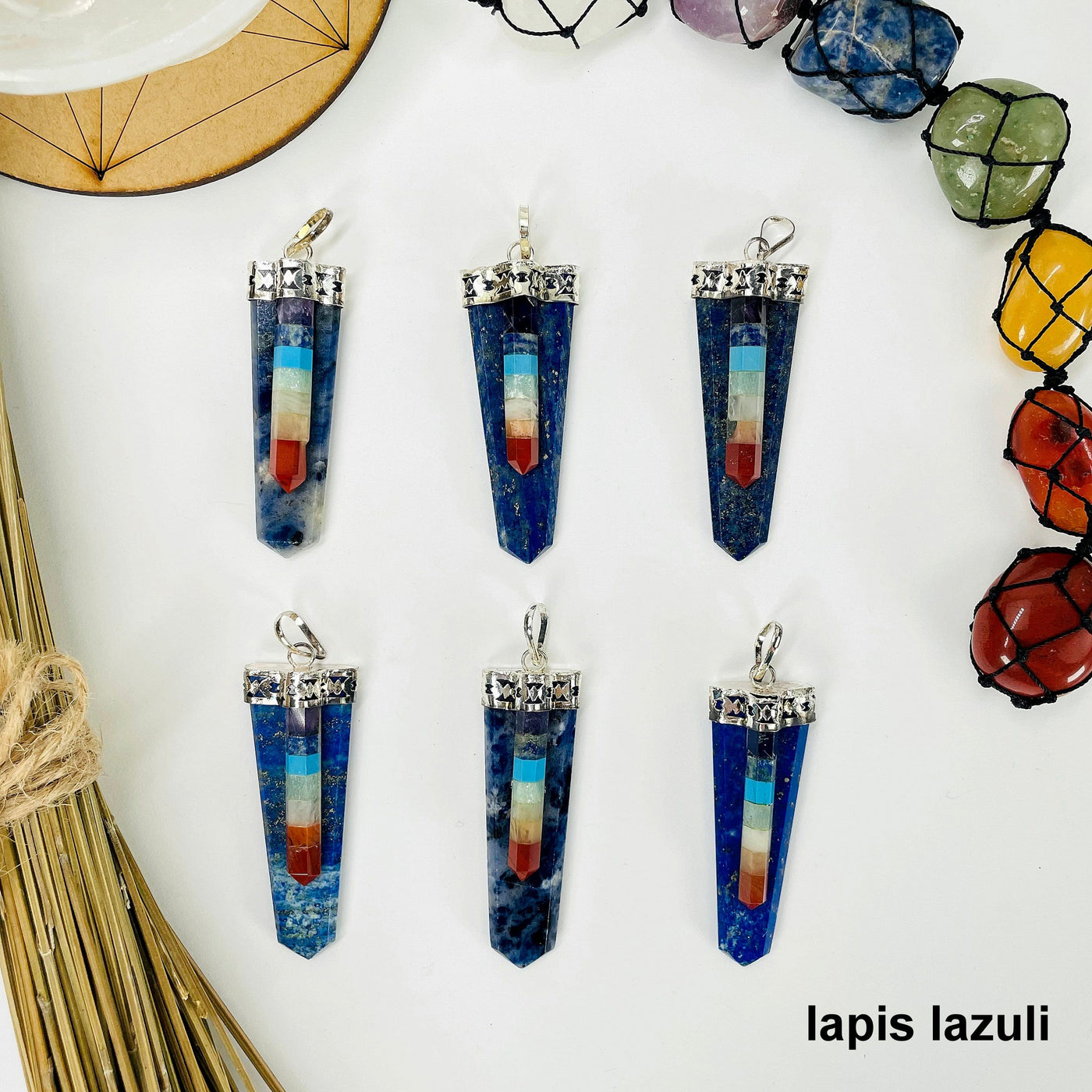 overhead view of six lapis lazuli polished point pendants with chakra point accents on white background with decorations for possible variations