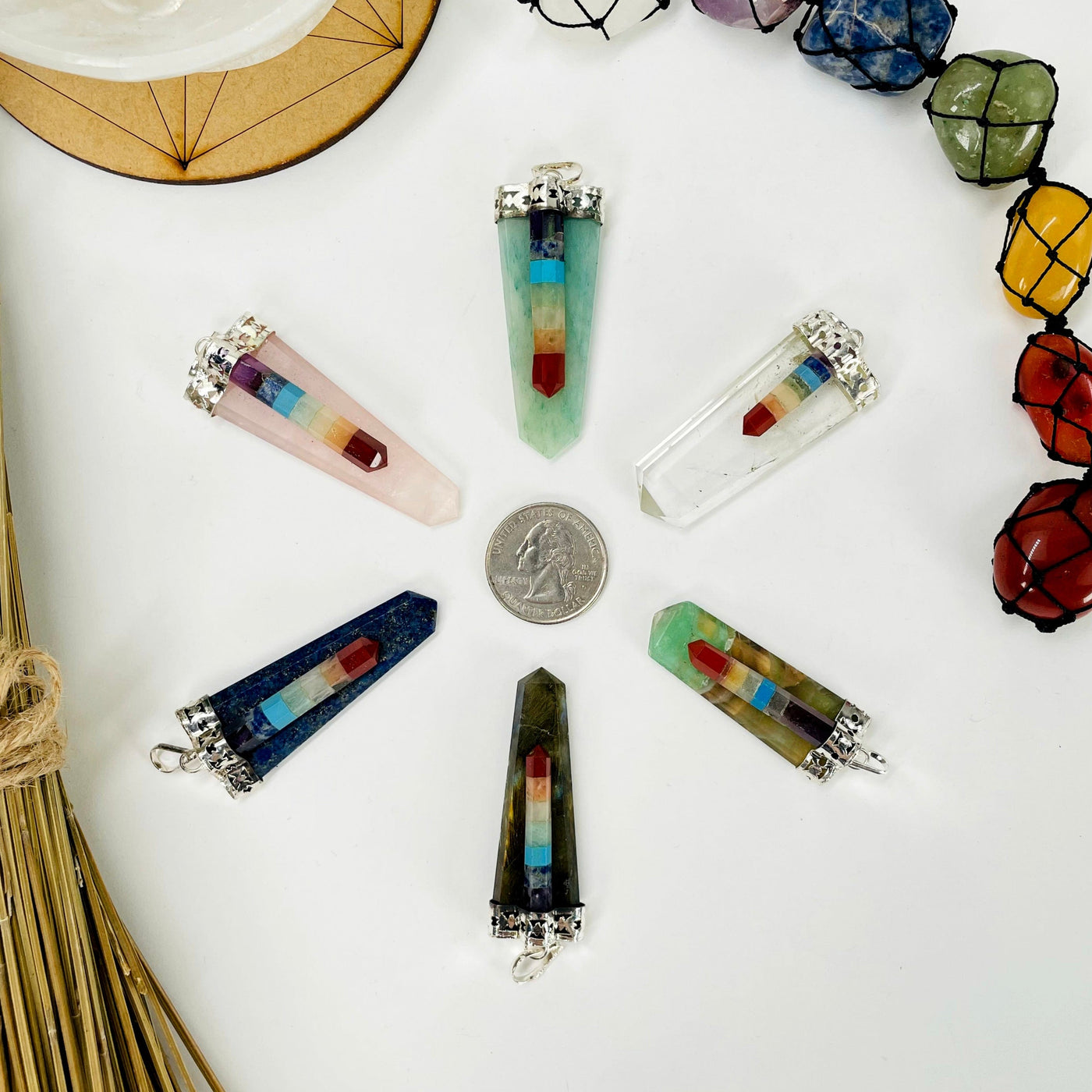 overhead view of one of each polished point pendants on white background surrounding a quarter for size reference