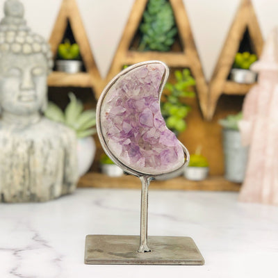 Amethyst moon cluster in a silver metal base with metal surrounding the moon. 