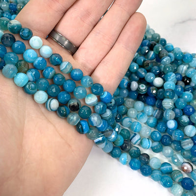 dyed teal agates in hand with white background
