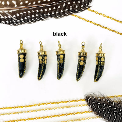 overhead view of five black petite mosaic horn pendants in a row on white background with decorations for possible variations