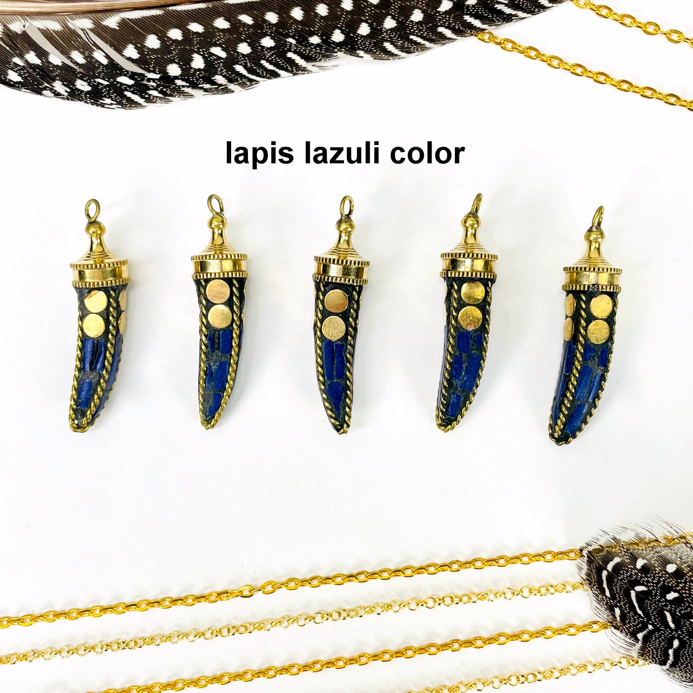 overhead view of five lapis lazuli color petite mosaic horn pendants in a row on white background with decorations for possible variations