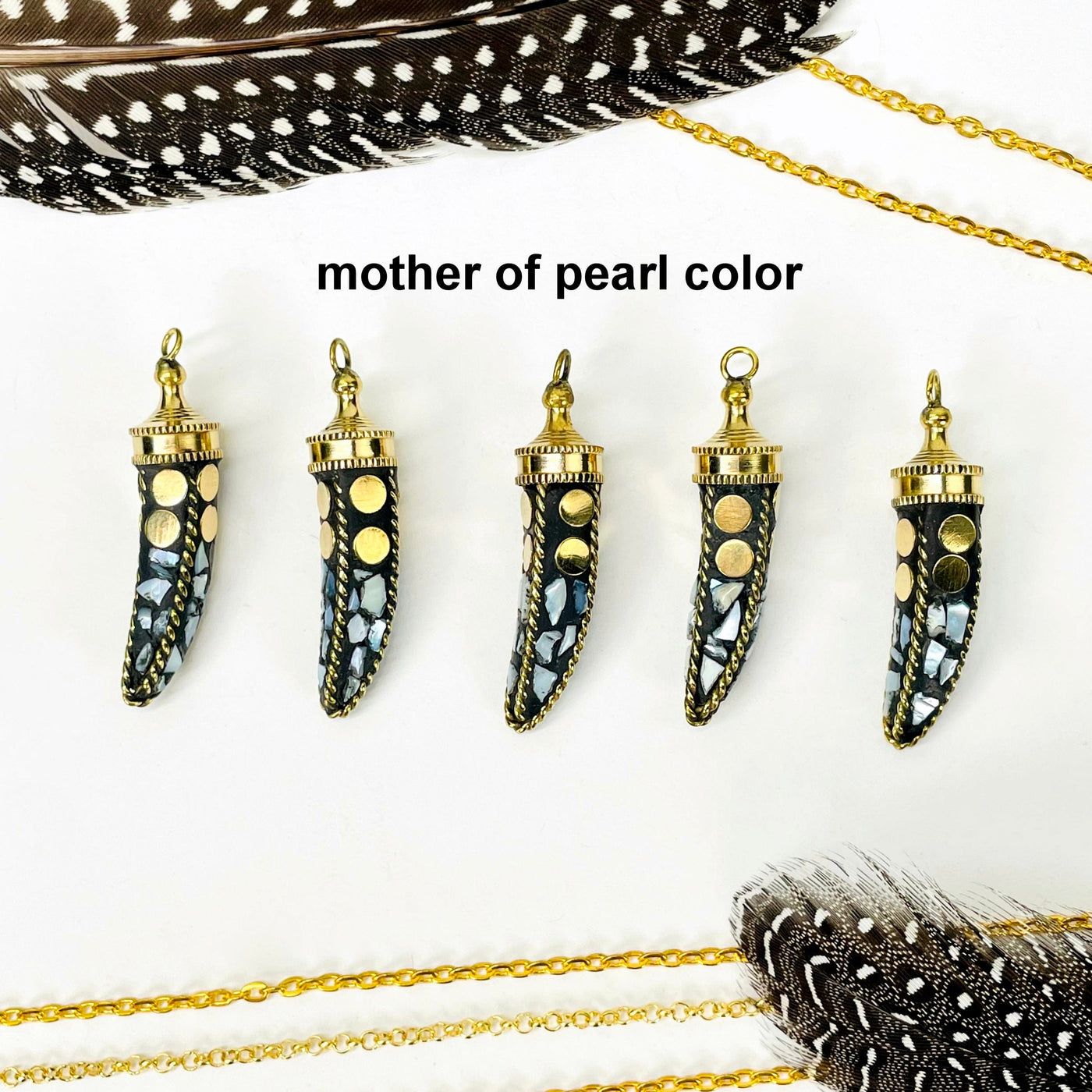 overhead view of five mother of pearl color petite mosaic horn pendants in a row on white background with decorations for possible variations