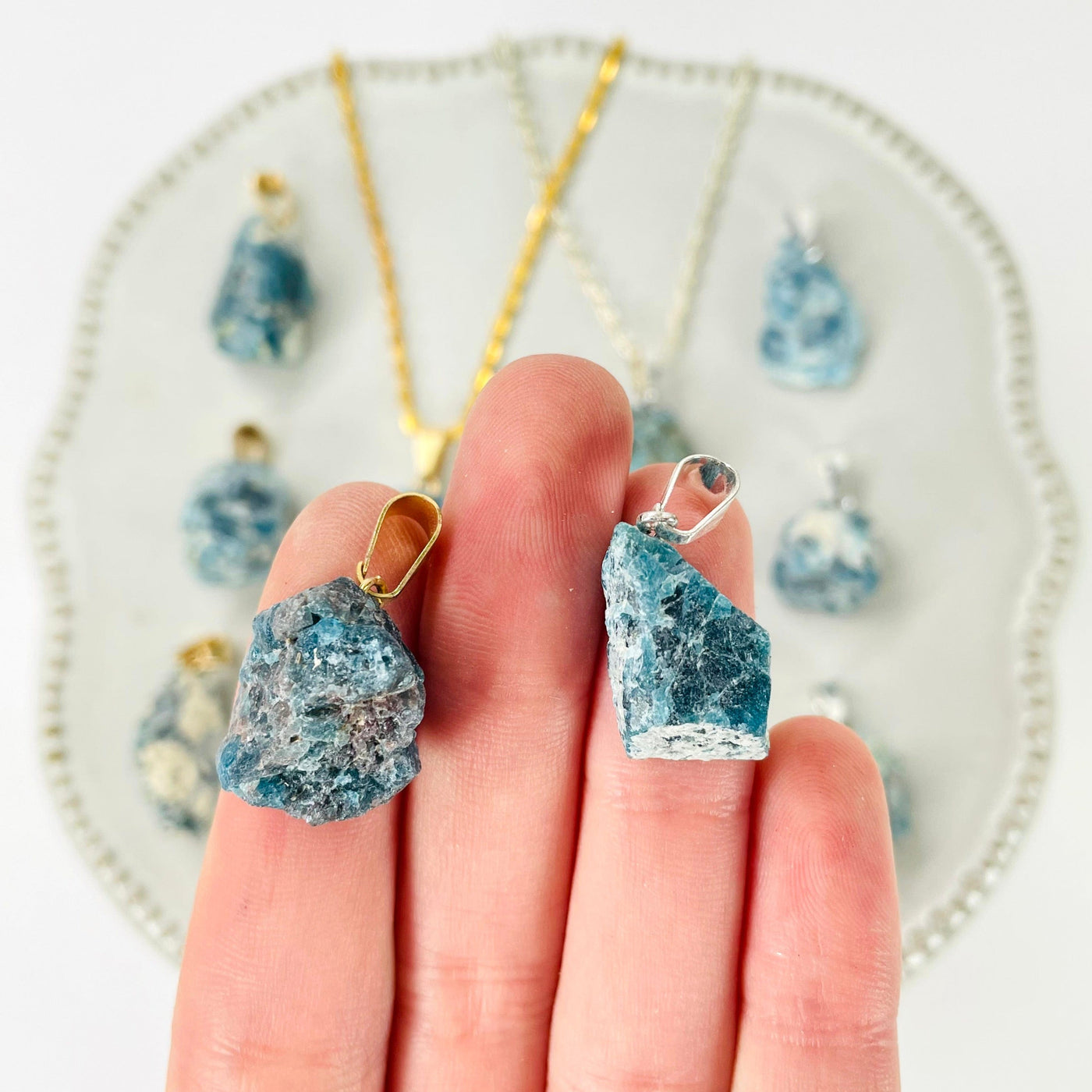 close up of one of each raw blue apatite chunk pendant finish options in hand for finish comparison and size reference