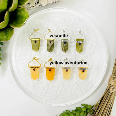 overhead view of two gold and two silver vesonite and yellow aventurine shield pendants