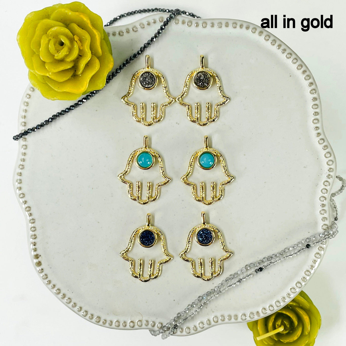 overhead view of two of each gold hamsa hand pendant stone options for finish reference