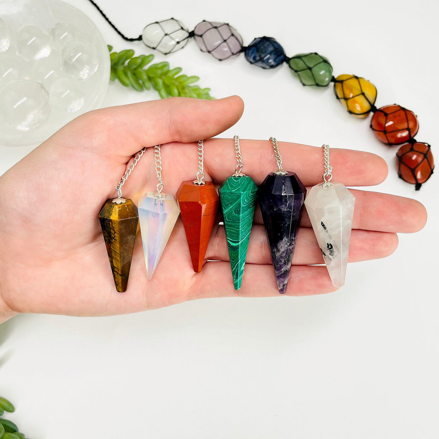 six different pendulum pendants in hand for size reference