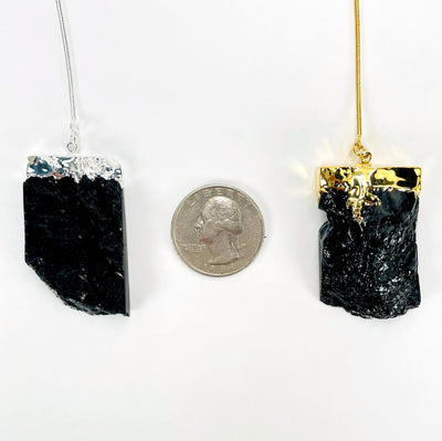 close up of one gold and one silver obsidian chunk with a quarter for size reference