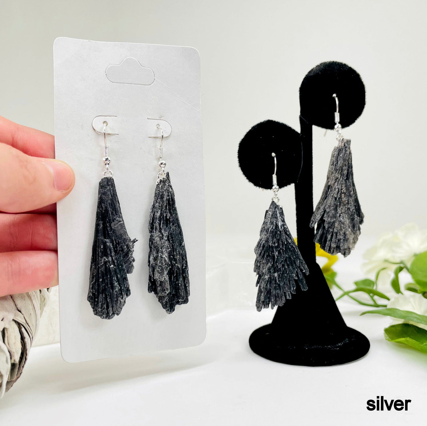 one silver black kyanite fan dangle earring pair on earring display and a second one in its packaging in hand for possible variations
