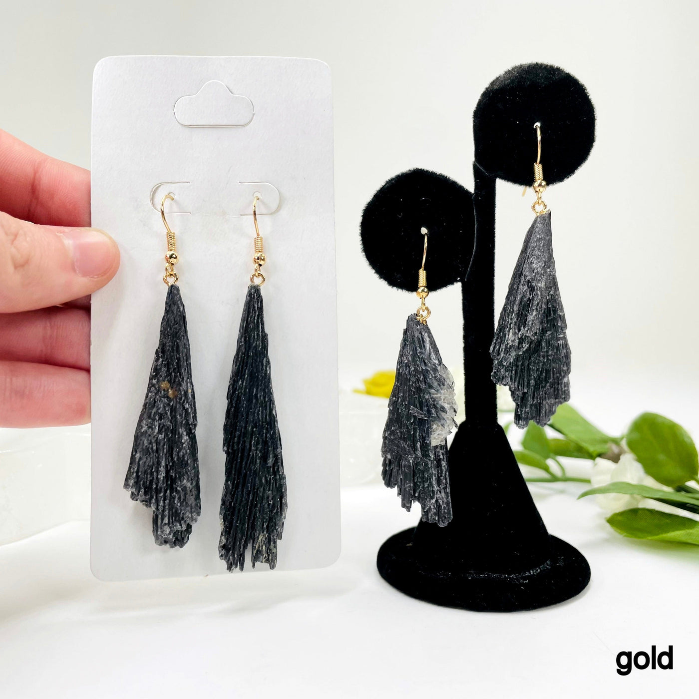 one gold black kyanite fan dangle earring pair on earring display and a second one in its packaging in hand for possible variations