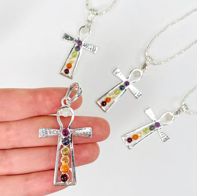 one chakra ankh pendant necklace in hand with three others in the background