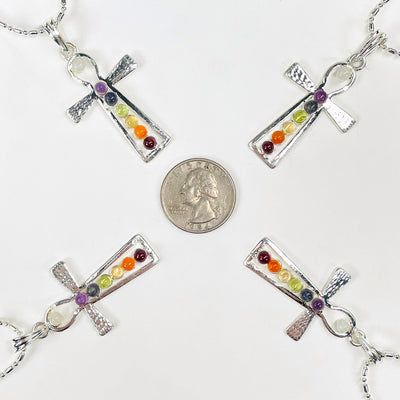 four chakra ankh pendant necklaces surrounding a quarter for size reference