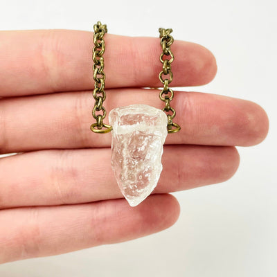 close up of tier 1 rough crystal quartz pendant in hand for size reference and details