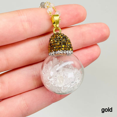 close up of one gold glass sphere pendant necklace in hand for finish and size reference