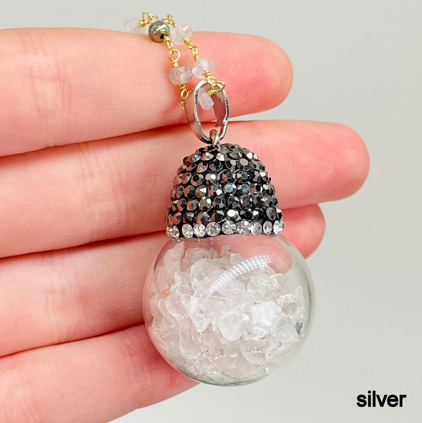 close up of one silver glass sphere pendant necklace in hand for finish and size reference