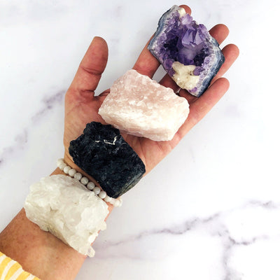amethyst cluster rose quartz black tourmaline and crystal quartz cluster in a woman's hand . 3 stones fit in her open hand and one is on her wrist