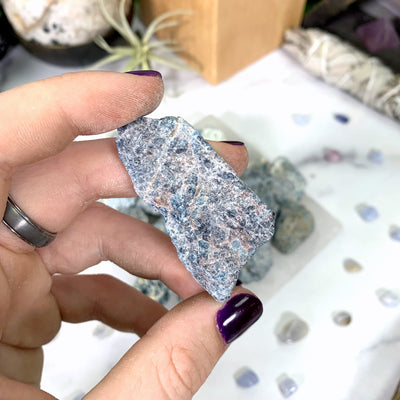 a different blue apatite stone in hand with marble background