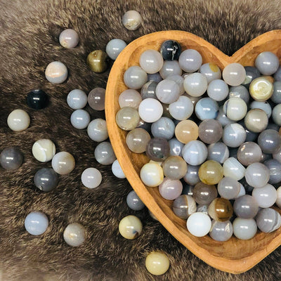 Picture of agate spheres displayed in a heart wooden bowl. 