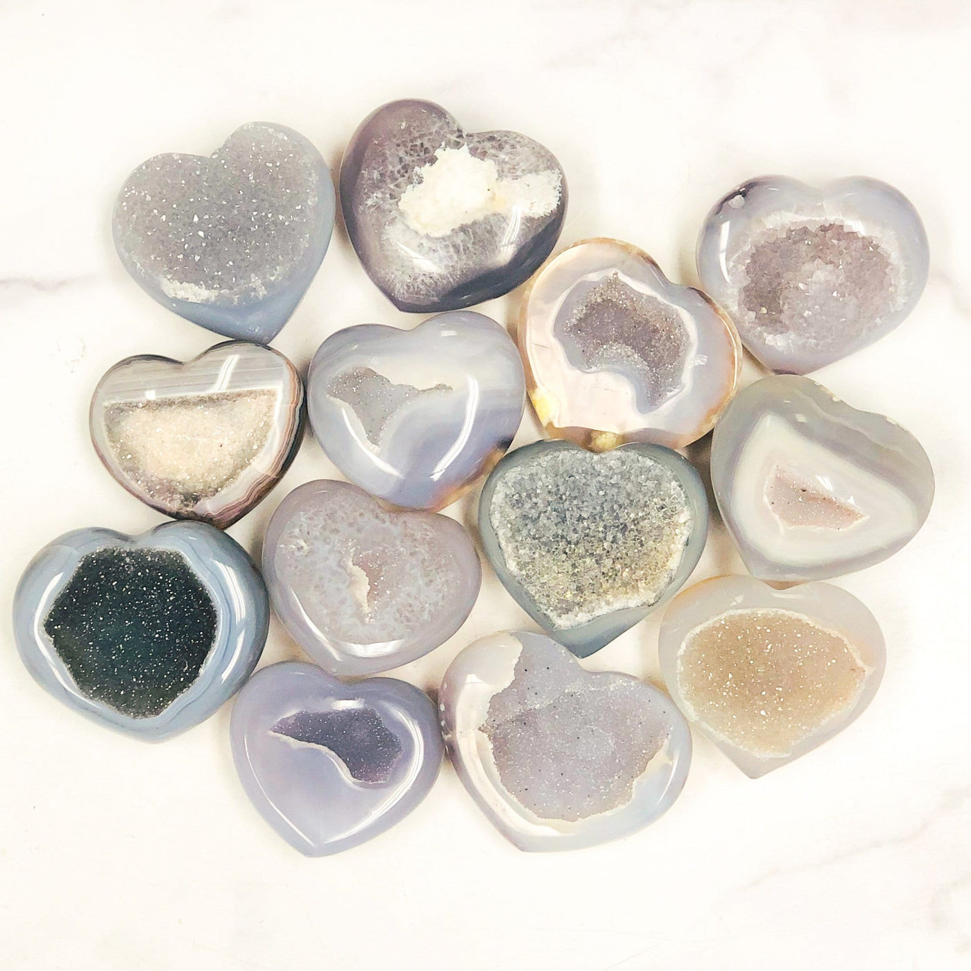 Front facing agate hearts with druzy on a white background displaying color, pattern and druzy variation.