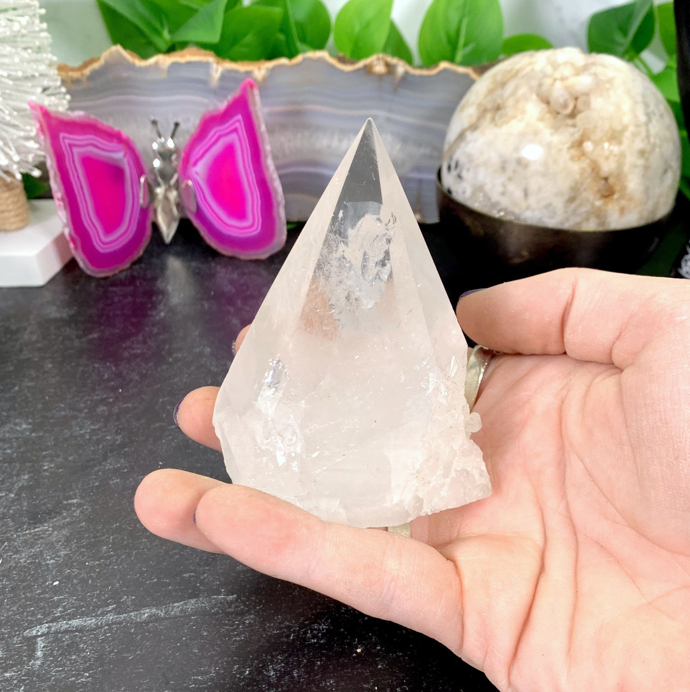 hand holding up Crystal Quartz Point with decorations in the background