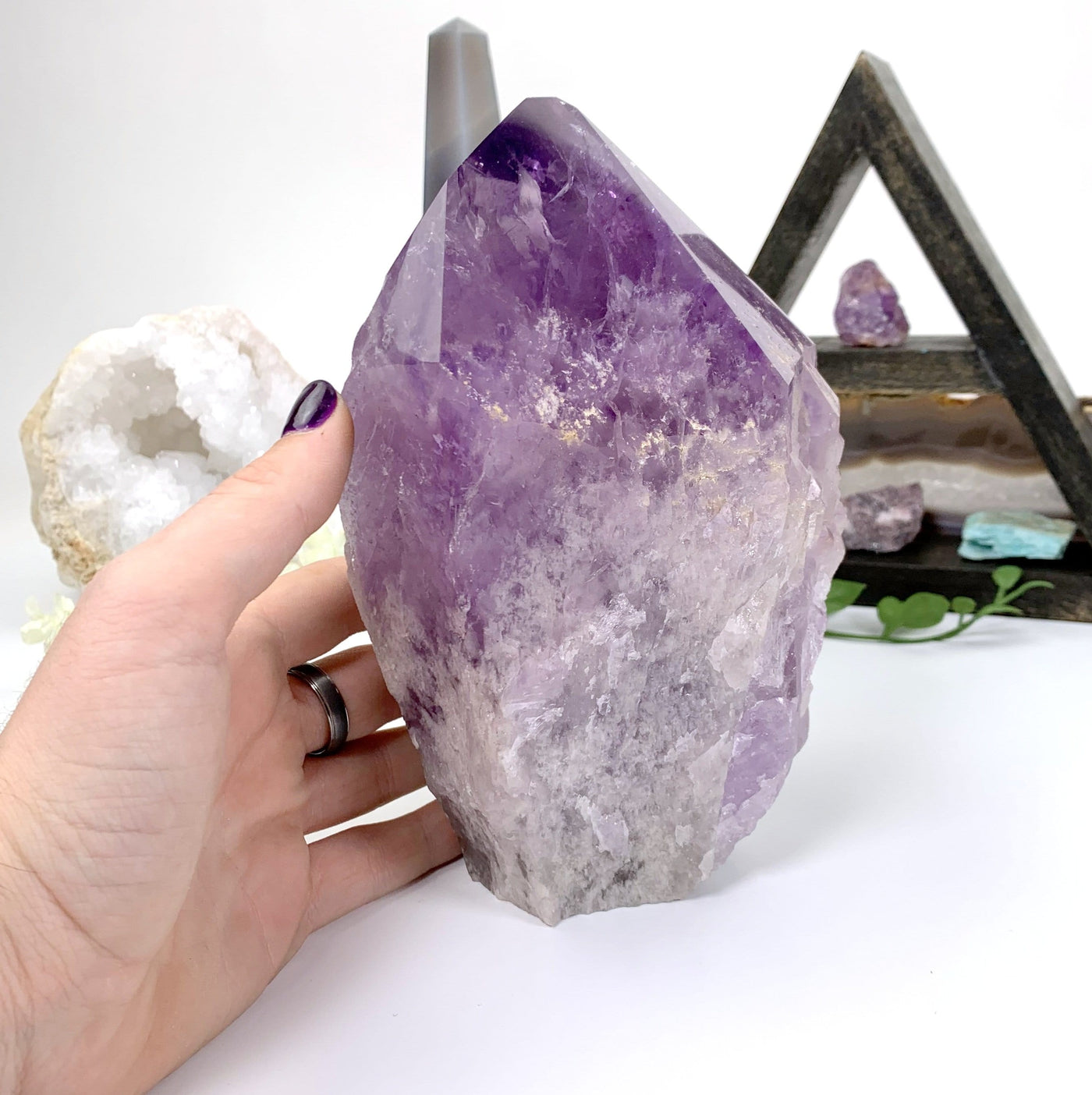 Back view of High Quality Amethyst Point, hand placed on the side of it for size reference.
