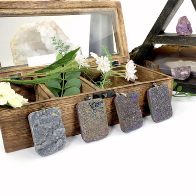 4 Rainbow Titanium Druzy Pendants leaning on wooden box with decorations in the background
