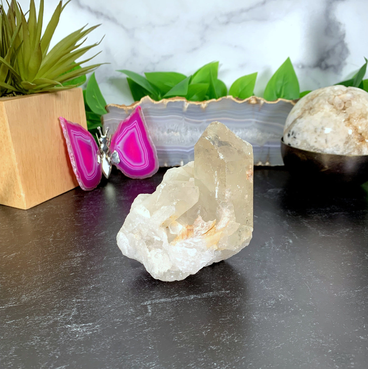 A one of a kind piece of a tangerine quartz cluster on a table 
