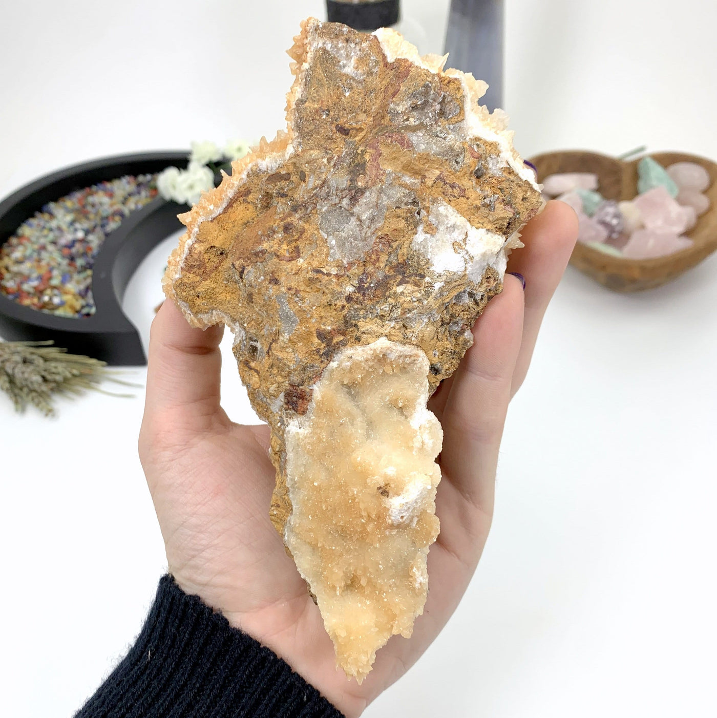 bottom angle of calcite druzy cluster in hand with white background