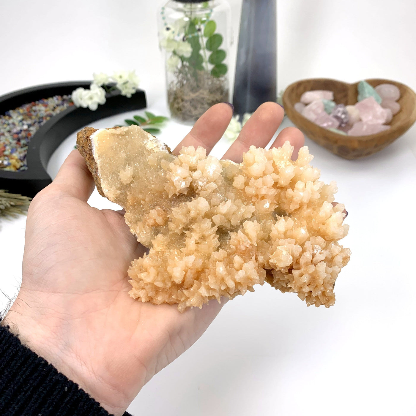 calcite druzy cluster in hand with a white background