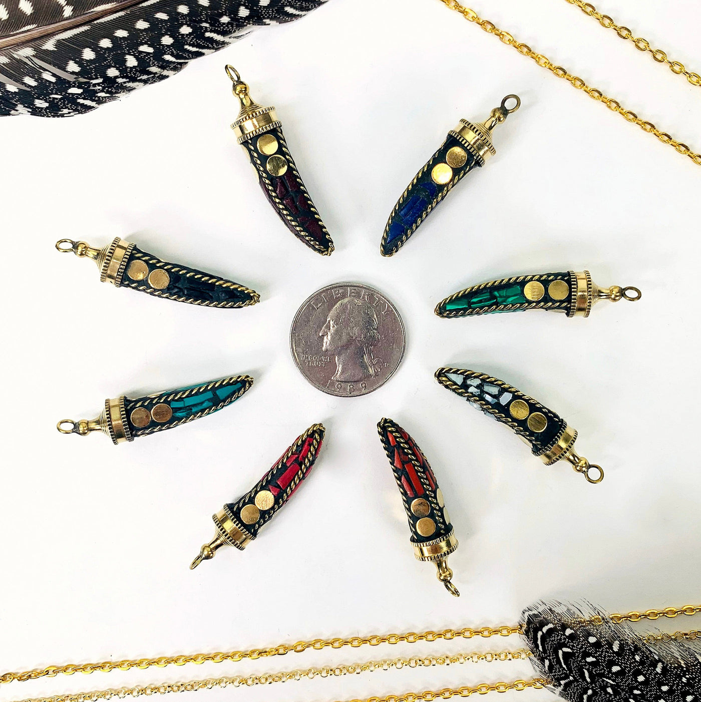 overhead view of one of each petite mosaic horn pendant color options surrounding a quarter for size reference