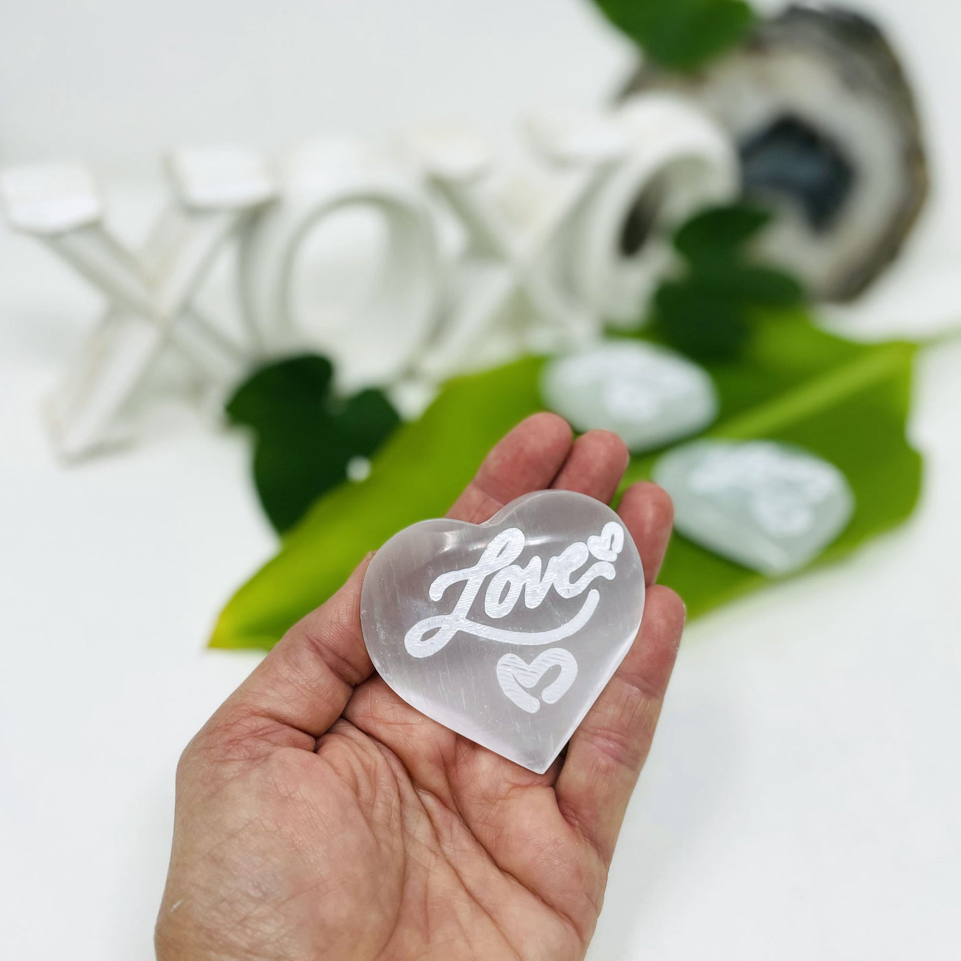 selenite engraved "love" heart stone in hand for size reference