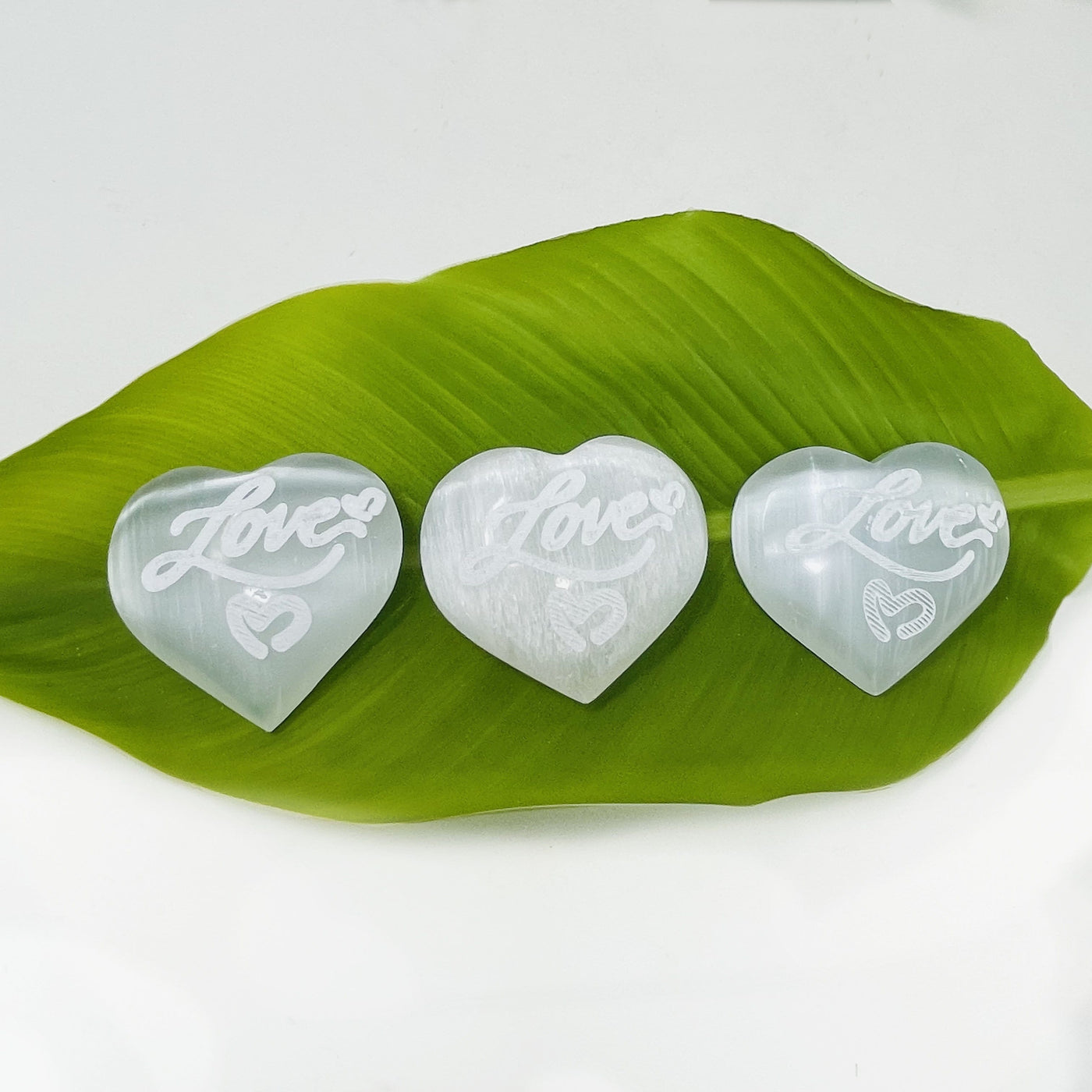 overhead view of selenite engraved "love" heart stones for details and possible variations