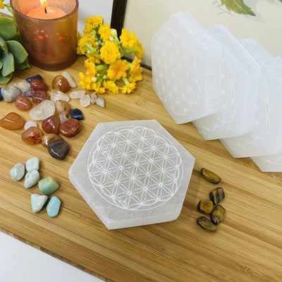 overhead view of selenite hexagon engraved with flower of life for engraving details with others on display in background