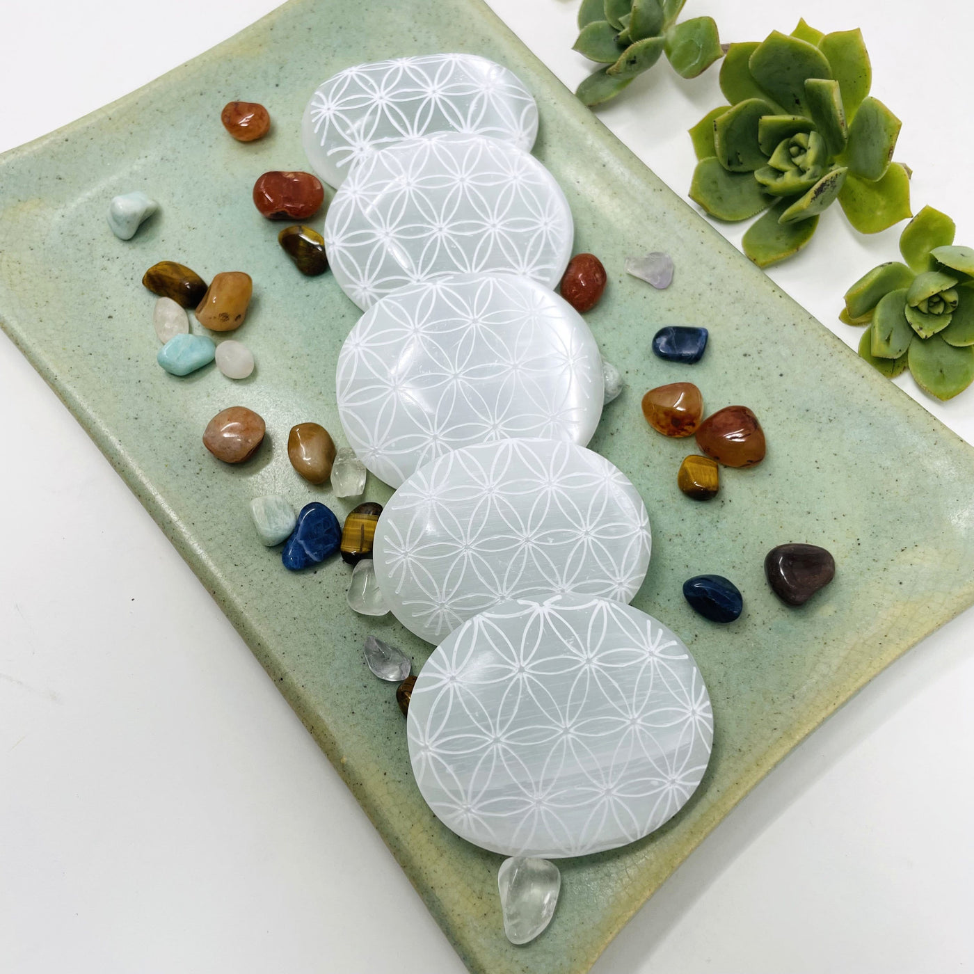 many selenite flower of life engraved palm stones on display
