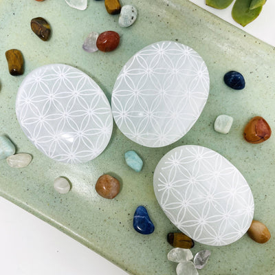 overhead view of selenite flower of life engraved palm stones for engraving details and possible variations 