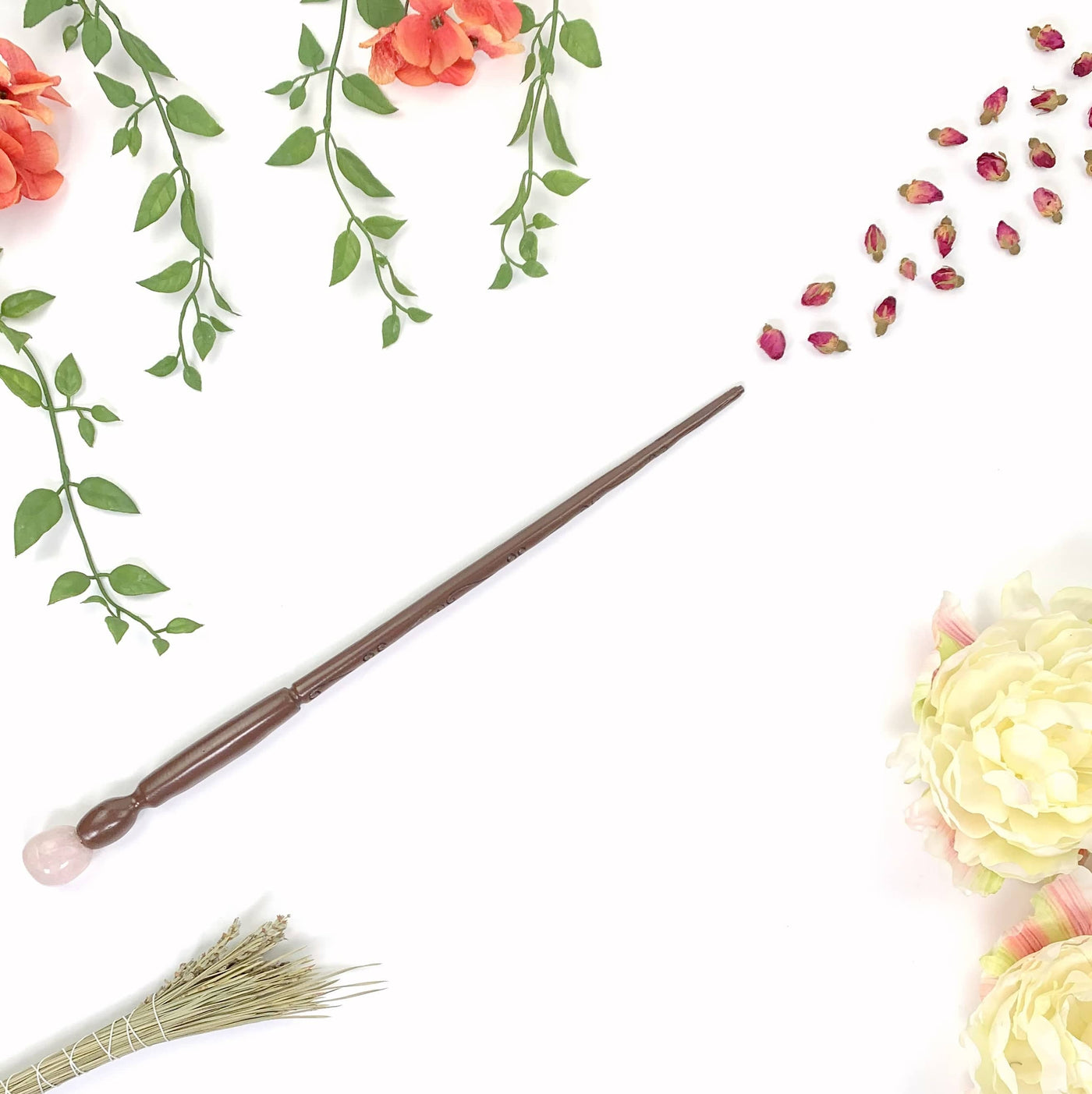 Enchantment Wand with rose buds in front of it and other floral decorations on white background