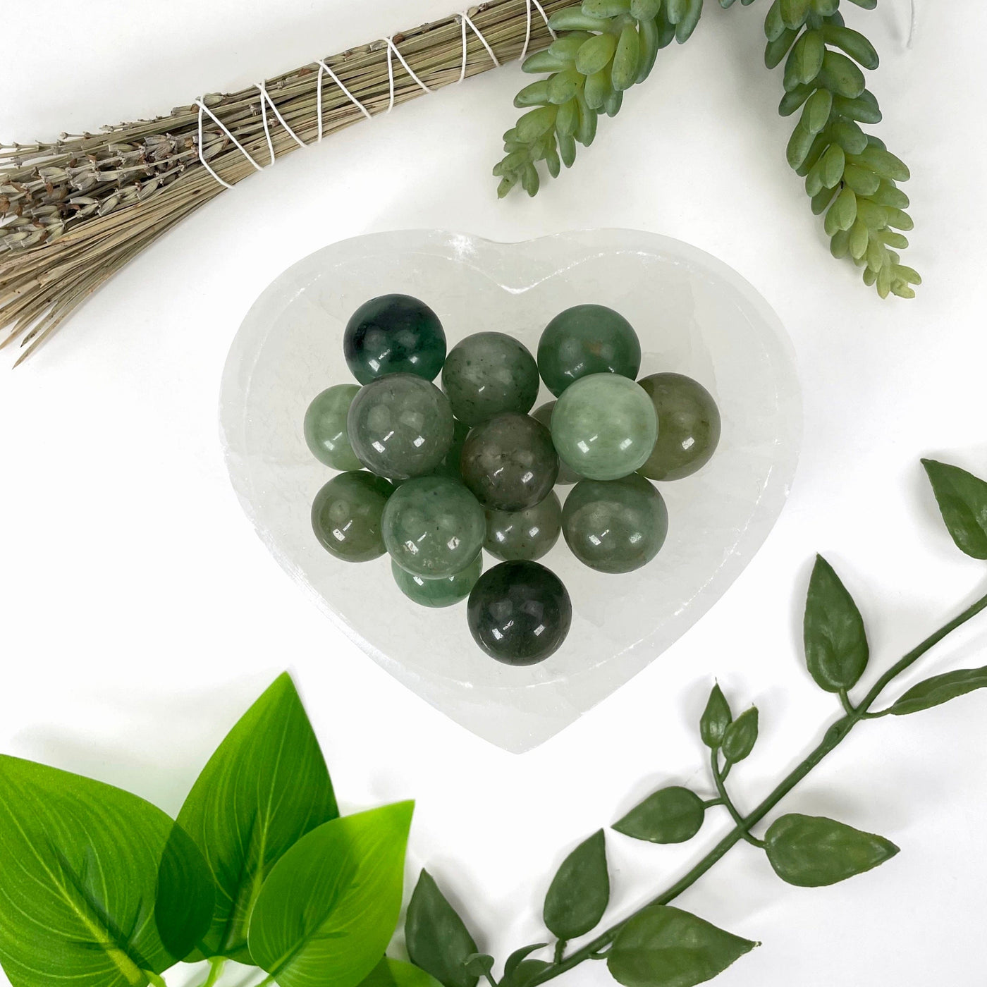 overhead view of many green aventurine spheres in heart bowl for possible variations