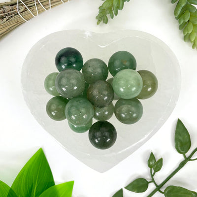 close up of many green aventurine spheres in heart bowl for details and possible variations