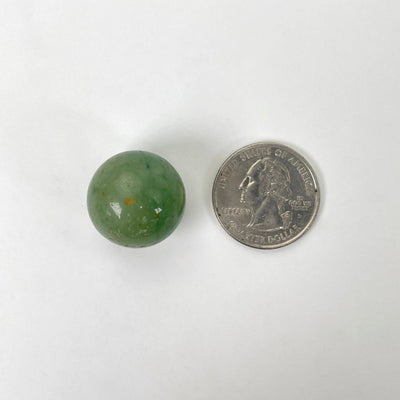 close up of one green aventurine sphere on white background with quarter for size reference