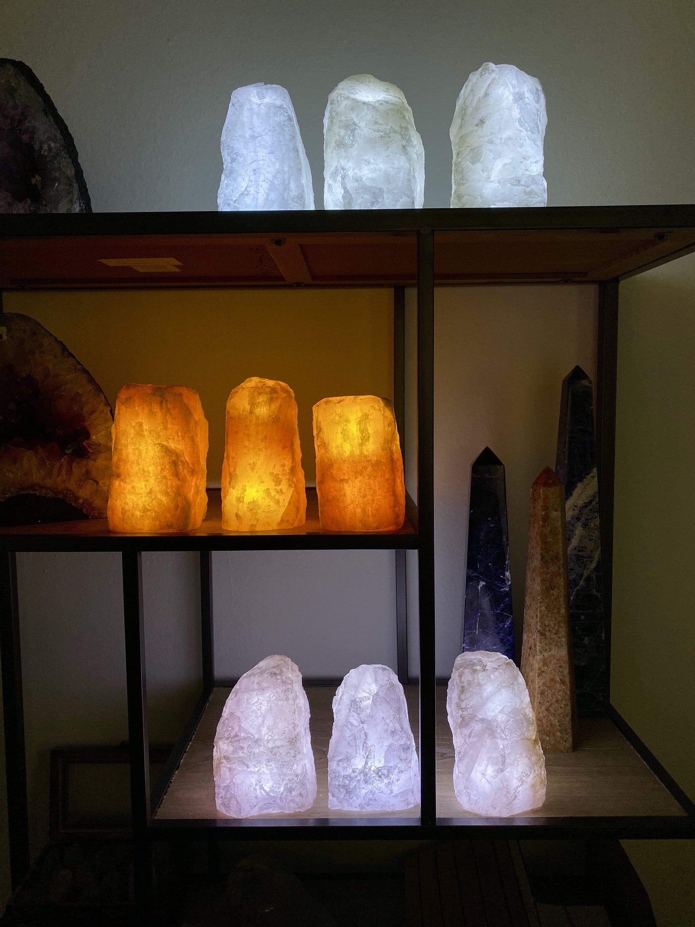 6 Rough Stone Lamps in groups of 3 lit up in a dark room with other crystals